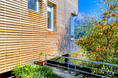Foto de fachada de casa contemporánea pequeña de dos plantas con revestimiento de madera, tejado plano y techo verde