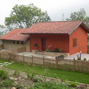 Immagine della facciata di una casa unifamiliare rossa country a un piano con rivestimenti misti, tetto a capanna e copertura in tegole
