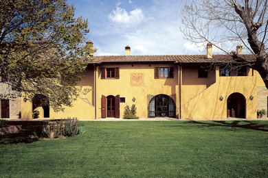Esempio della villa ampia gialla country a due piani con rivestimenti misti