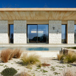 Esempio della villa beige contemporanea a un piano con rivestimento in pietra, tetto piano e copertura verde