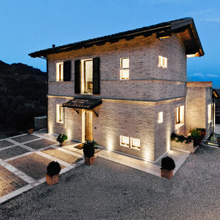 Ispirazione per la facciata di una casa unifamiliare beige country a piani sfalsati di medie dimensioni con rivestimento in mattoni, tetto a capanna e copertura in tegole