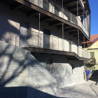 Foto della facciata di una casa grande a tre piani con rivestimento in legno, tetto a capanna e copertura mista