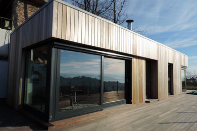 This is an example of a small and beige contemporary bungalow detached house in Other with wood cladding, a flat roof and a green roof.