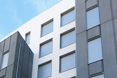 Modelo de fachada actual grande de tres plantas con revestimientos combinados y tejado plano