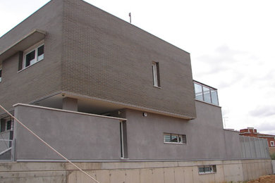 Diseño de fachada gris contemporánea grande de dos plantas con revestimiento de ladrillo y tejado plano