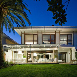 Imagen de fachada de casa blanca, contemporánea, grande, de dos plantas, con revestimientos combinados y tejado de un solo tendido