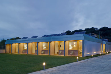 Modelo de fachada gris minimalista grande de una planta con revestimientos combinados, techo verde y tejado plano