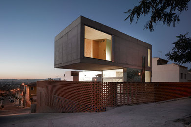Inspiration pour une grande façade de maison grise design en béton à niveaux décalés avec un toit plat.