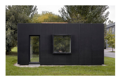 Ejemplo de fachada negra contemporánea de tamaño medio de una planta con revestimientos combinados y tejado plano