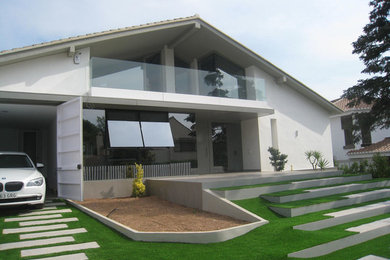 Modelo de fachada blanca actual de tamaño medio de dos plantas con revestimientos combinados y tejado a dos aguas