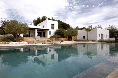 Modelo de fachada blanca mediterránea de tamaño medio de dos plantas con revestimientos combinados y tejado plano