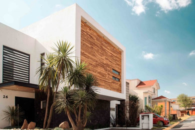 Modelo de fachada blanca minimalista de tamaño medio de dos plantas con revestimiento de madera y tejado plano