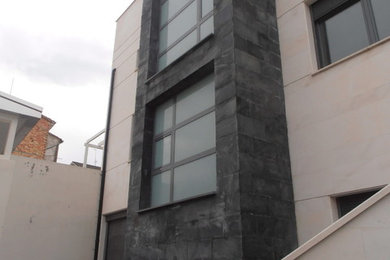 Modelo de fachada blanca contemporánea de tamaño medio de tres plantas con revestimientos combinados y tejado plano