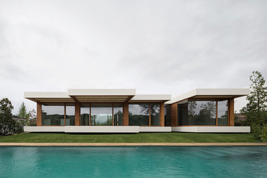 Ejemplo de fachada marrón moderna grande de una planta con revestimiento de vidrio y tejado plano