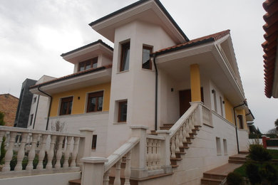 Diseño de fachada amarilla clásica renovada de tamaño medio de tres plantas con revestimientos combinados y tejado a dos aguas