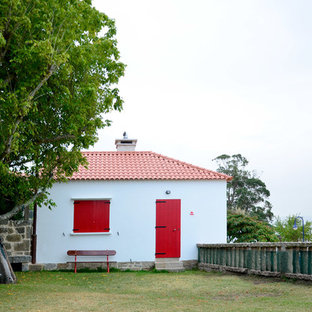 Imagen de fachada de casa blanca, marinera, pequeña, de dos plantas, con revestimiento de piedra, tejado a dos aguas y tejado de teja de barro
