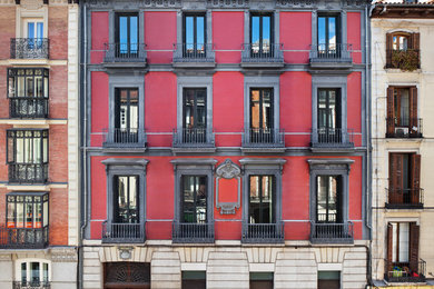 Ejemplo de fachada roja tradicional grande de tres plantas con revestimientos combinados y tejado plano