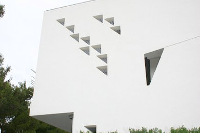 Ejemplo de fachada blanca moderna de tamaño medio de dos plantas con revestimiento de estuco y tejado plano