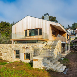 Modelo de fachada de casa beige, contemporánea, grande, de dos plantas, con revestimientos combinados y tejado a dos aguas