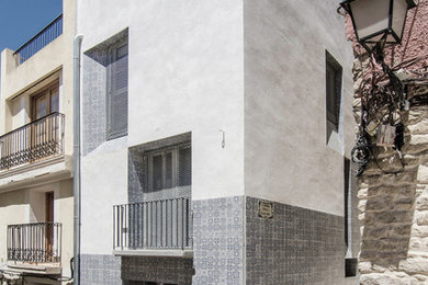 Diseño de fachada gris mediterránea de tamaño medio de tres plantas con revestimiento de hormigón y tejado plano