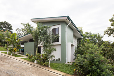 Modelo de fachada de casa verde moderna a niveles con revestimiento de hormigón y tejado de metal