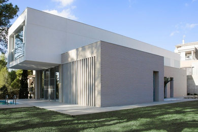 Example of a large minimalist white two-story brick flat roof design in Valencia