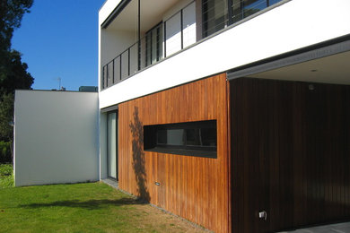 Ejemplo de fachada blanca minimalista de tamaño medio de dos plantas con revestimiento de madera y tejado plano