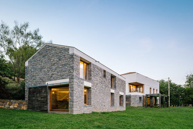 Large farmhouse gray two-story stone gable roof idea in Madrid