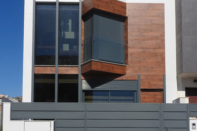 Modelo de fachada de casa multicolor minimalista de tamaño medio de tres plantas con revestimientos combinados, tejado plano y tejado de varios materiales