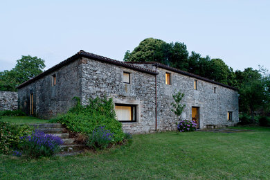 Imagen de fachada gris de estilo de casa de campo de tamaño medio de dos plantas con revestimiento de piedra y tejado a cuatro aguas