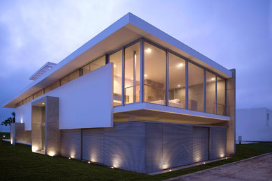 Diseño de fachada blanca actual grande de tres plantas con revestimiento de aglomerado de cemento y tejado plano