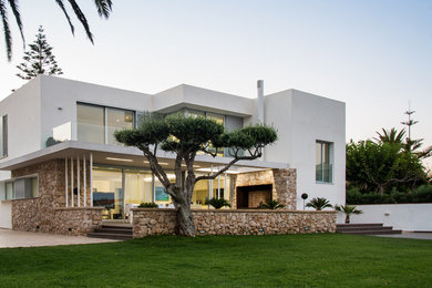Diseño de fachada blanca mediterránea de tamaño medio de dos plantas con revestimientos combinados y tejado plano