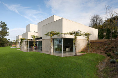 Ejemplo de fachada beige actual grande de dos plantas con revestimiento de hormigón y tejado plano