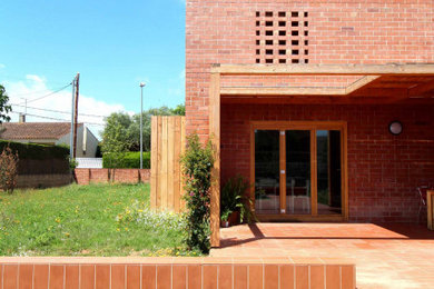 Diseño de fachada de casa moderna de tamaño medio de dos plantas con revestimiento de ladrillo y tejado plano