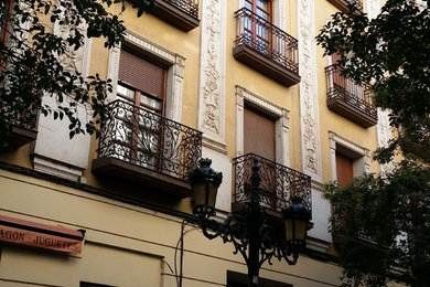 Ejemplo de fachada amarilla clásica de tamaño medio de tres plantas con revestimientos combinados