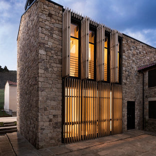 Foto de fachada de casa marrón, contemporánea, de tamaño medio, de tres plantas, con revestimiento de piedra, tejado a dos aguas y tejado de teja de barro