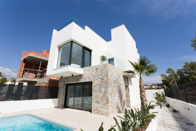 Foto de fachada de casa blanca mediterránea de tamaño medio de dos plantas con revestimientos combinados y tejado plano