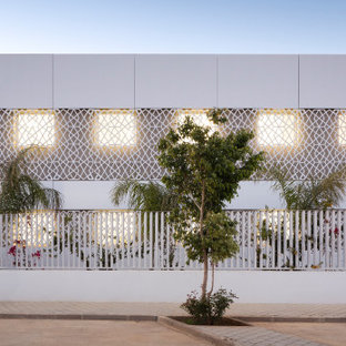 Diseño de fachada blanca, minimalista, grande, de tres plantas, con revestimiento de hormigón