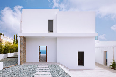 Diseño de fachada blanca actual de tamaño medio de dos plantas con tejado plano y revestimiento de estuco