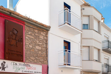 他の地域にある低価格の中くらいな地中海スタイルのおしゃれな家の外観 (漆喰サイディング、タウンハウス) の写真