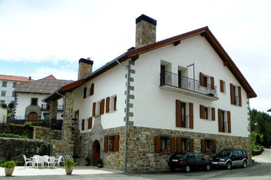 Foto de fachada blanca rústica de tamaño medio de tres plantas con revestimientos combinados y tejado a dos aguas