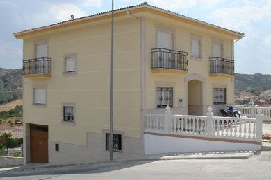 Modelo de fachada amarilla clásica renovada de tamaño medio de tres plantas con revestimientos combinados