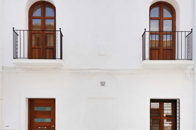 Foto della facciata di una casa piccola bianca classica a due piani con rivestimento in stucco e falda a timpano