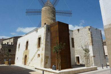 Diseño de fachada blanca mediterránea extra grande de tres plantas con revestimiento de piedra y tejado plano