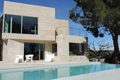 Cette photo montre une façade de maison beige tendance en pierre à un étage avec un toit plat.
