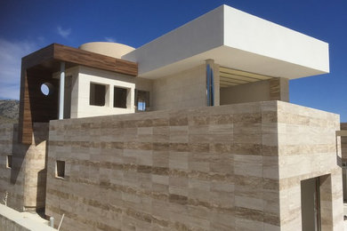 Modelo de fachada de casa beige grande de dos plantas con revestimiento de piedra y tejado plano