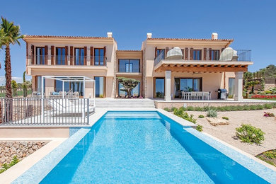 Inspiration pour une grande façade de maison beige méditerranéenne à un étage avec un revêtement mixte, un toit à deux pans et un toit en tuile.