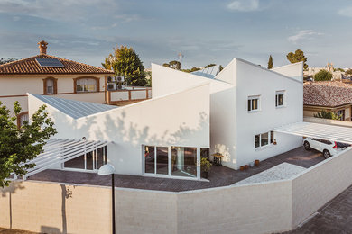 Ejemplo de fachada de casa blanca moderna de tamaño medio de dos plantas con revestimiento de estuco, tejado a cuatro aguas y tejado de metal