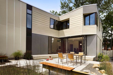 Cette image montre une grande façade de maison beige minimaliste à un étage avec un revêtement mixte et un toit plat.