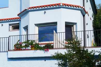 Modelo de fachada de casa azul costera de tamaño medio de tres plantas con revestimiento de estuco, tejado a dos aguas y tejado de teja de barro